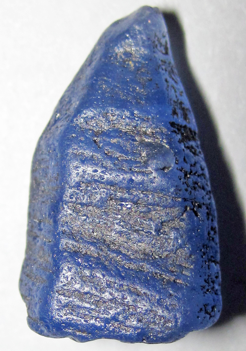 Rough blue sapphire crystal on a light background. Example photo, not a parcel for sale.