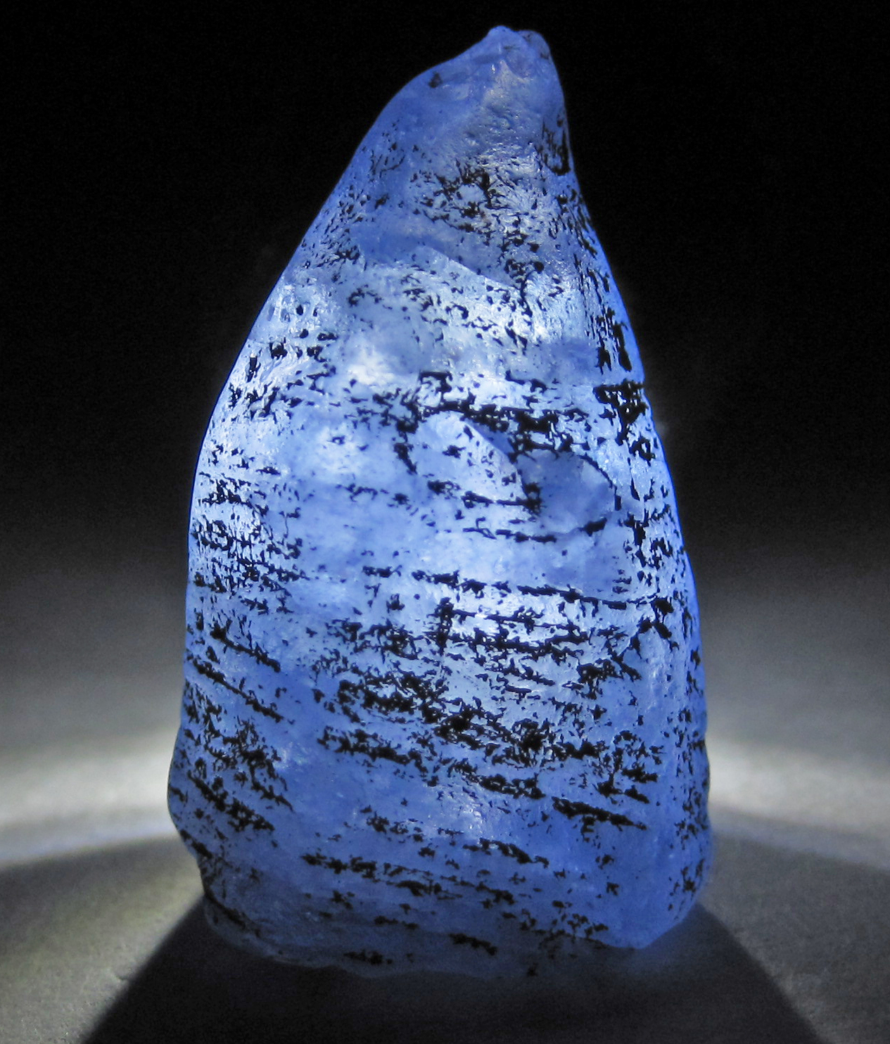 Backlit rough blue sapphire crystal — Pure Avi Gems illustrative photo, not current stock.
