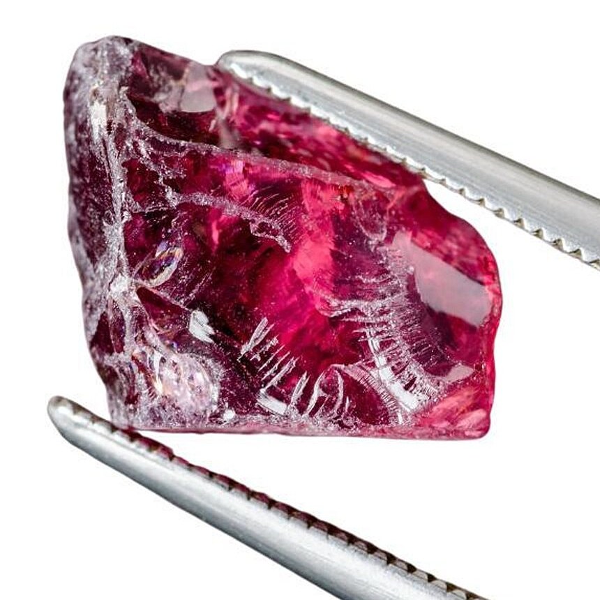 Rough red garnet held in tweezers. Example photo, not a parcel for sale.